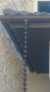 Decorative chain downspout on half-round gutter